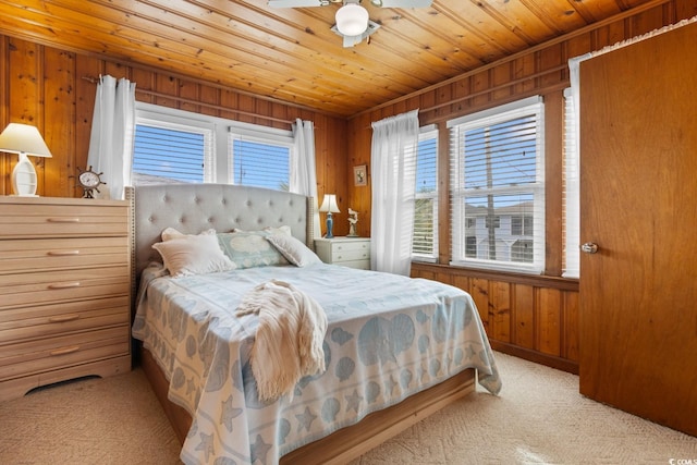 carpeted bedroom featuring wood walls, ceiling fan, and wooden ceiling