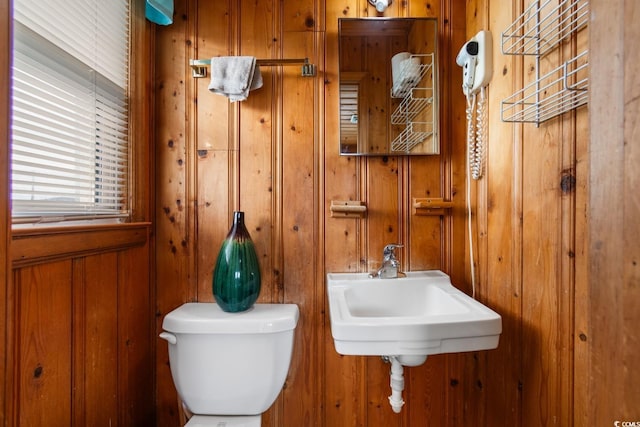 bathroom with wooden walls, sink, and toilet