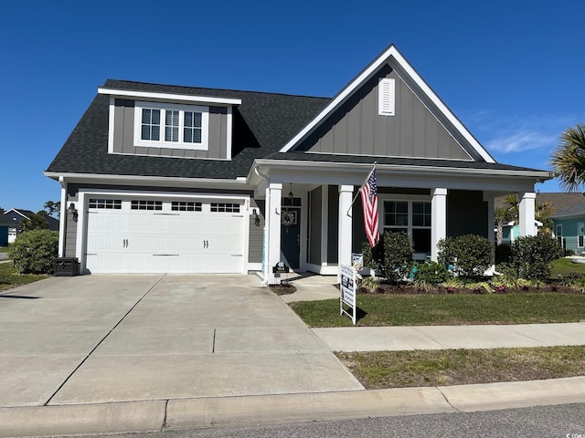 view of front of home with a shingled roof, a garage, board and batten siding, covered porch, and driveway