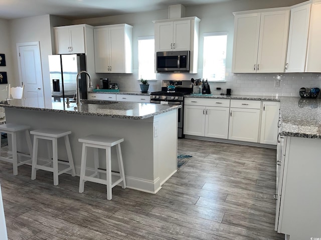 kitchen with white cabinetry, appliances with stainless steel finishes, stone countertops, and a center island