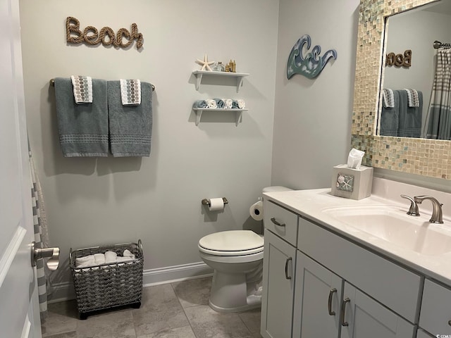 bathroom featuring baseboards, vanity, and toilet