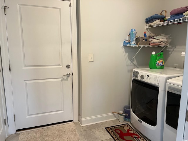 laundry room featuring laundry area, light tile patterned floors, baseboards, and washing machine and clothes dryer