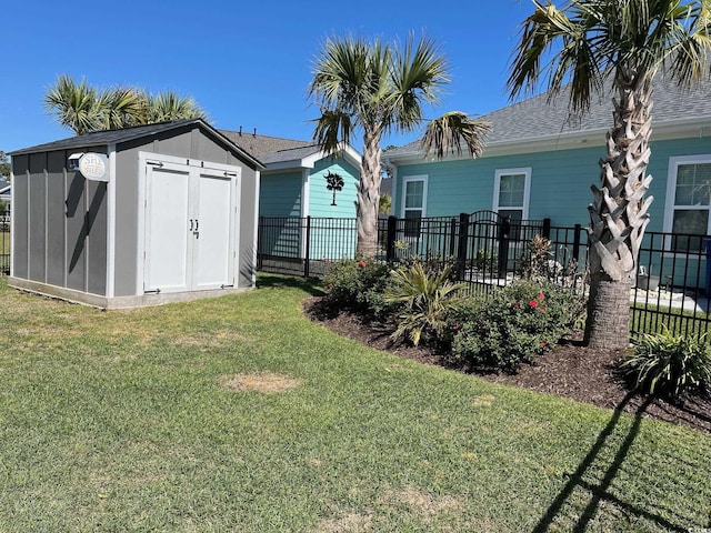 back of property with a lawn, a storage shed, fence, an outdoor structure, and a shingled roof