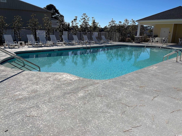 community pool with a patio area and fence