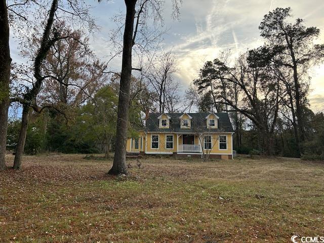 cape cod house featuring a yard and covered porch