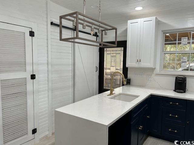 kitchen featuring sink, white cabinets, blue cabinetry, and kitchen peninsula