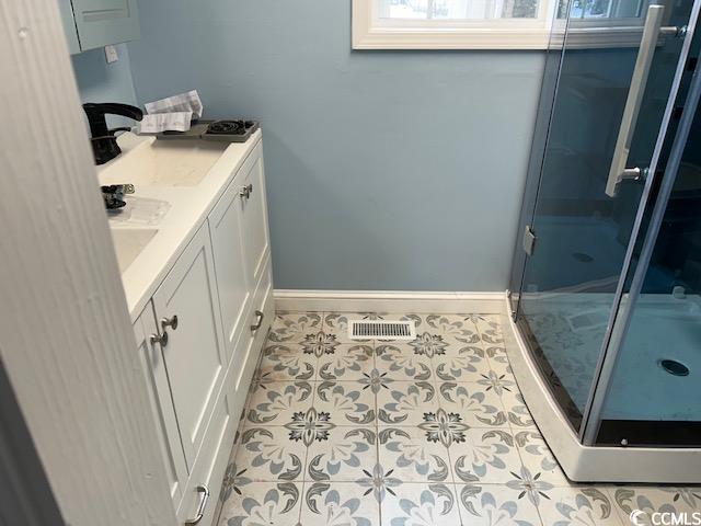 bathroom with tile patterned flooring, vanity, and walk in shower