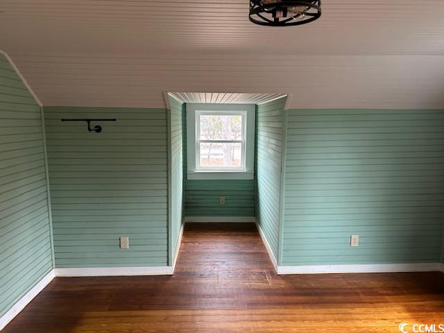 interior space with wooden walls, dark hardwood / wood-style floors, and vaulted ceiling