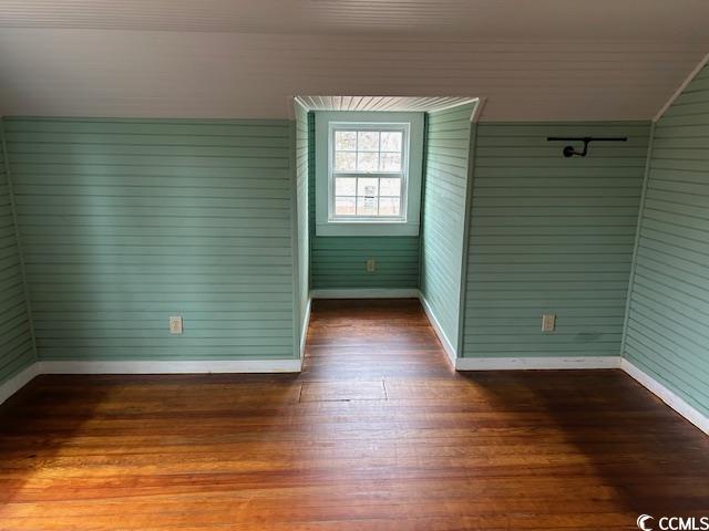 empty room featuring wood-type flooring and wood walls