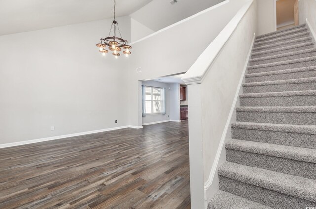 stairway featuring an inviting chandelier, hardwood / wood-style flooring, and high vaulted ceiling