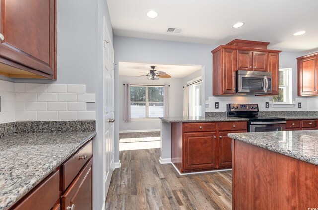 kitchen with ceiling fan, light stone counters, dark wood-type flooring, and appliances with stainless steel finishes