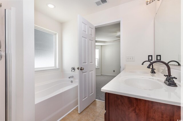 bathroom featuring tile patterned flooring, vanity, and a tub