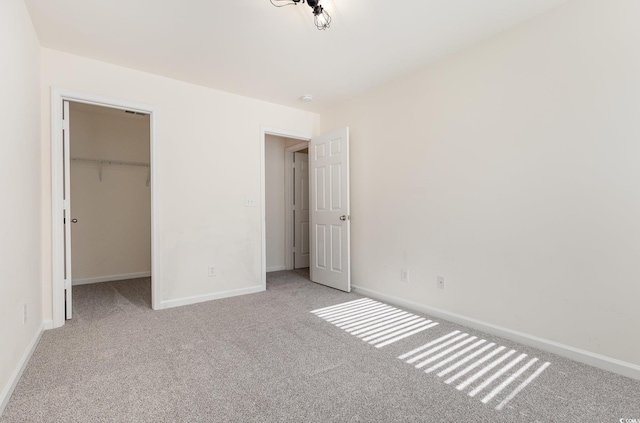 unfurnished bedroom featuring a spacious closet, a closet, and light colored carpet