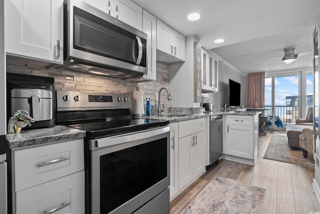 kitchen featuring appliances with stainless steel finishes, backsplash, light hardwood / wood-style floors, and white cabinetry