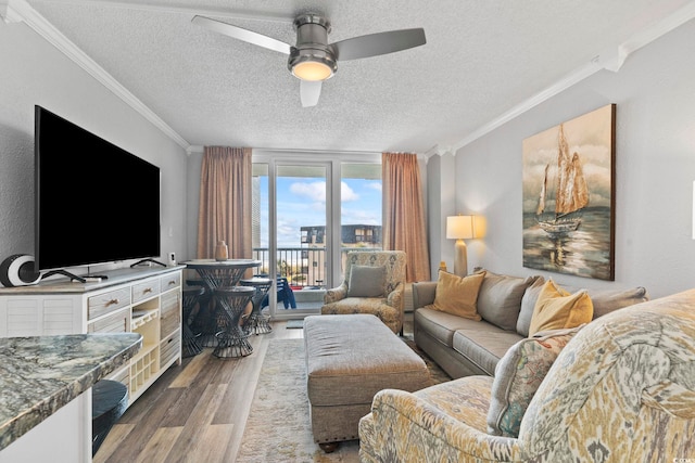 living room featuring ceiling fan, light hardwood / wood-style floors, crown molding, and a textured ceiling