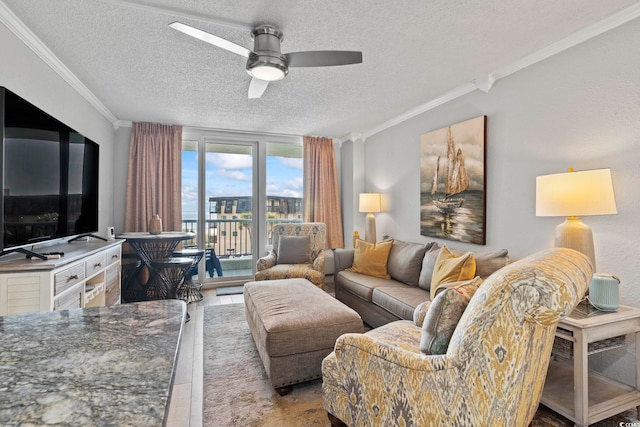 living room featuring light wood-type flooring, a textured ceiling, ceiling fan, and ornamental molding