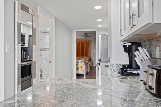 kitchen featuring light stone countertops, ceiling fan, stainless steel appliances, wood-type flooring, and white cabinets