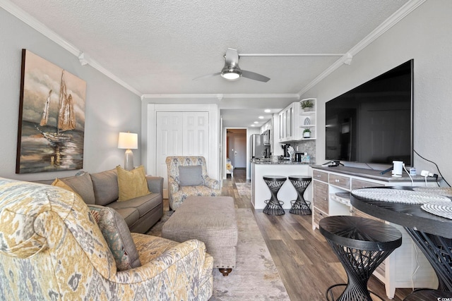 living room with hardwood / wood-style floors, a textured ceiling, ceiling fan, and ornamental molding