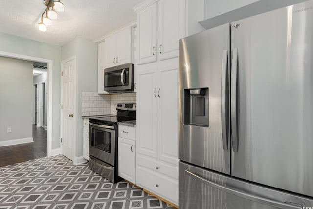 kitchen featuring stainless steel appliances, backsplash, dark stone counters, a textured ceiling, and white cabinets