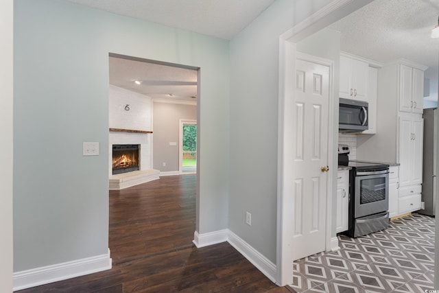 kitchen with dark hardwood / wood-style floors, white cabinetry, stainless steel appliances, and a textured ceiling