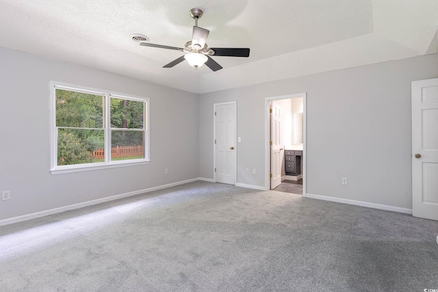 unfurnished bedroom with carpet, ensuite bathroom, ceiling fan, and a textured ceiling