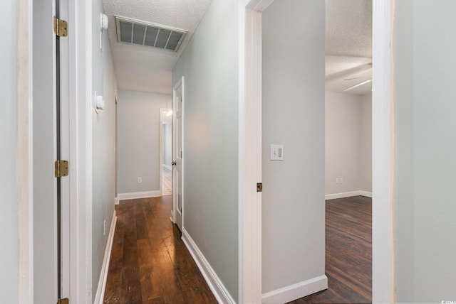 hall featuring a textured ceiling and dark hardwood / wood-style flooring