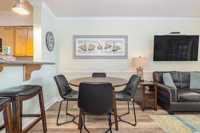 dining space with light wood-type flooring and ornamental molding