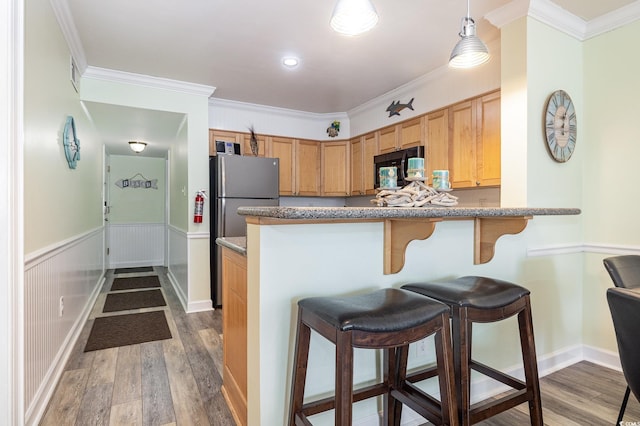 kitchen featuring hardwood / wood-style floors, pendant lighting, a kitchen bar, kitchen peninsula, and crown molding