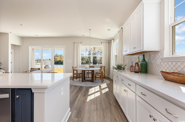 kitchen with a wealth of natural light, dark hardwood / wood-style flooring, white cabinets, and hanging light fixtures