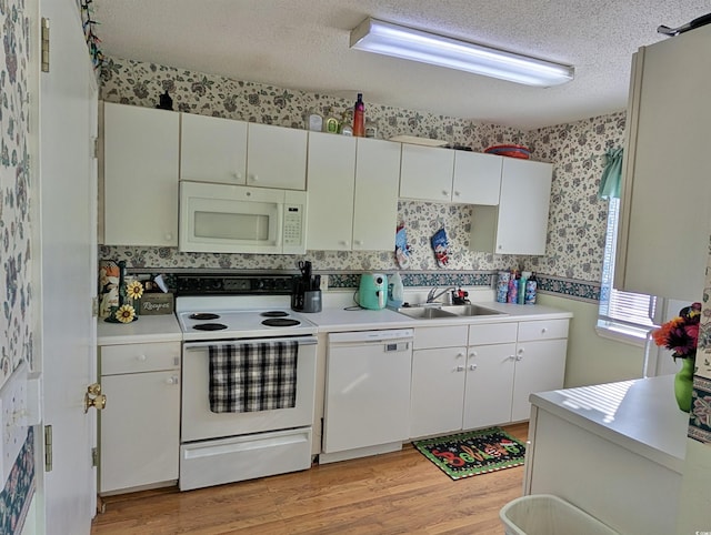 kitchen with white appliances, light hardwood / wood-style flooring, white cabinetry, and sink