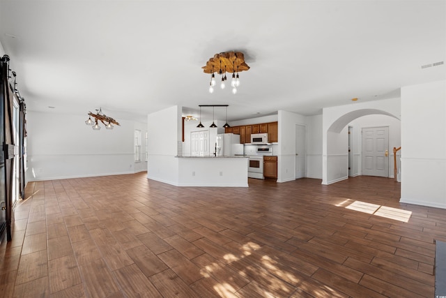 unfurnished living room with a notable chandelier and dark hardwood / wood-style floors