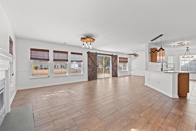 unfurnished living room with a barn door, sink, and light wood-type flooring