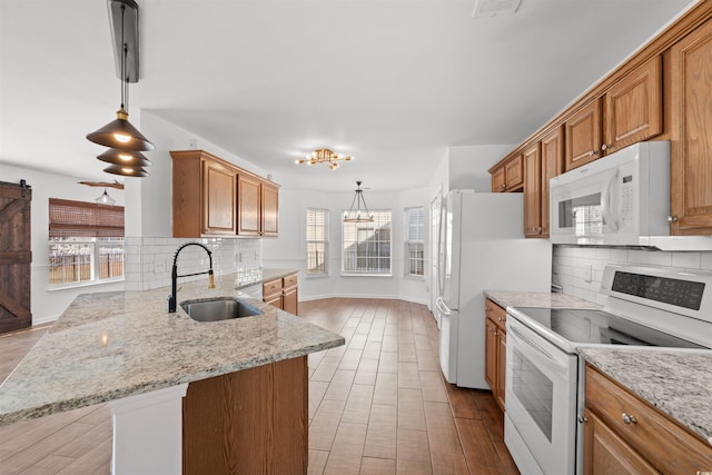 kitchen featuring plenty of natural light, white appliances, sink, and hanging light fixtures