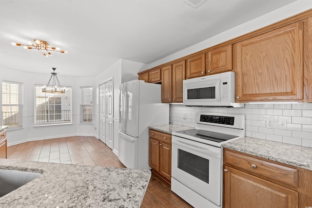 kitchen featuring pendant lighting, white appliances, backsplash, light hardwood / wood-style floors, and a chandelier