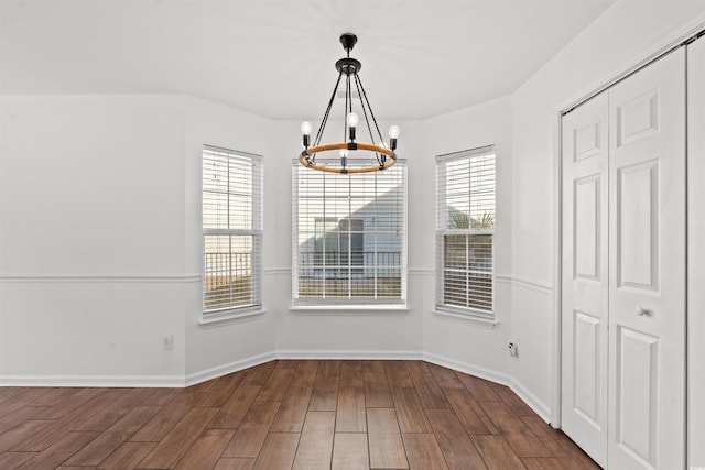 unfurnished dining area with dark hardwood / wood-style flooring, plenty of natural light, and a notable chandelier