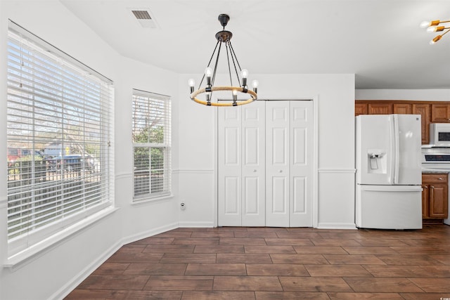 unfurnished dining area featuring dark wood-type flooring and an inviting chandelier