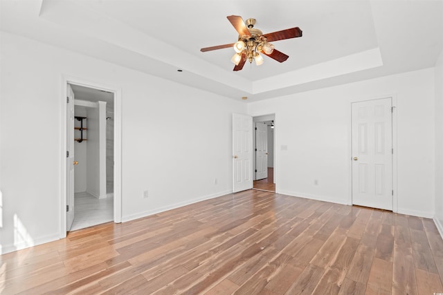 unfurnished bedroom featuring hardwood / wood-style floors, ceiling fan, a raised ceiling, and ensuite bathroom