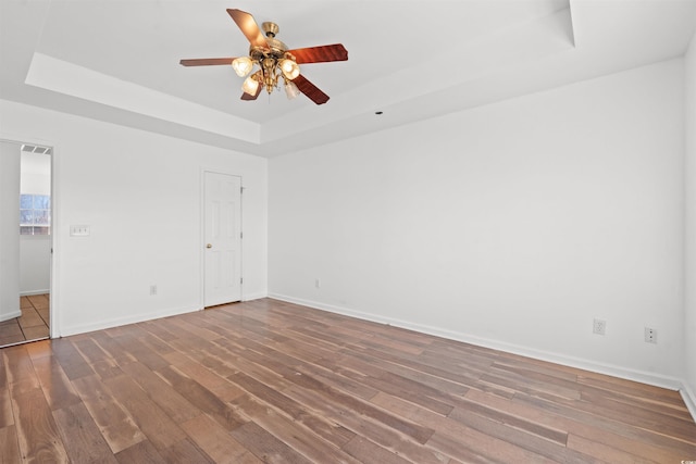 unfurnished room with hardwood / wood-style flooring, a raised ceiling, and ceiling fan