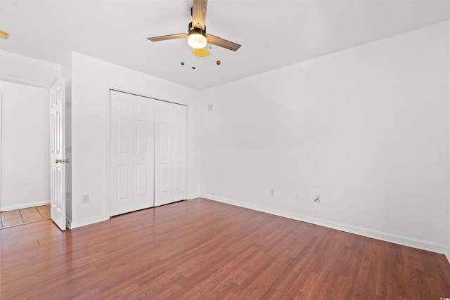 unfurnished bedroom with ceiling fan, a closet, and hardwood / wood-style flooring