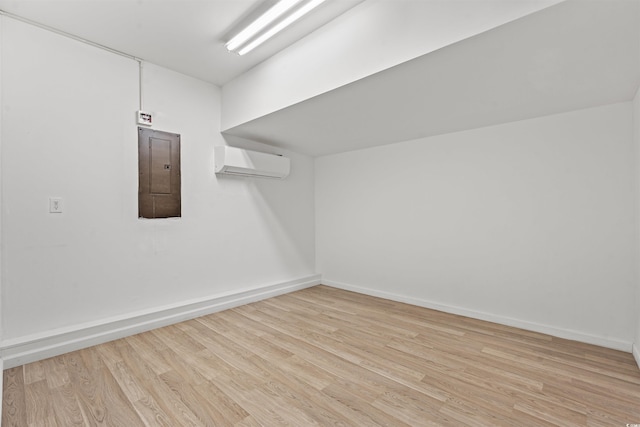 additional living space featuring electric panel, light hardwood / wood-style flooring, and a wall mounted air conditioner