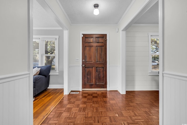 foyer featuring a wealth of natural light, crown molding, a textured ceiling, and wainscoting