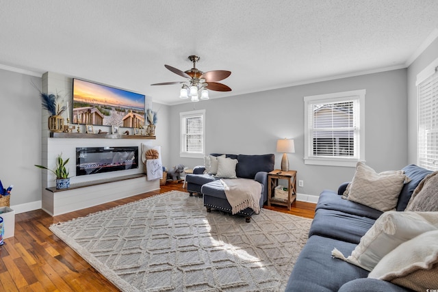 living room featuring crown molding, wood finished floors, and a glass covered fireplace