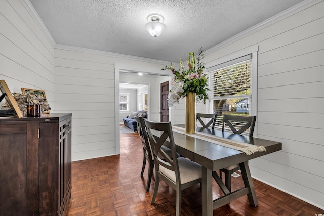 dining area featuring ornamental molding, a textured ceiling, and wooden walls