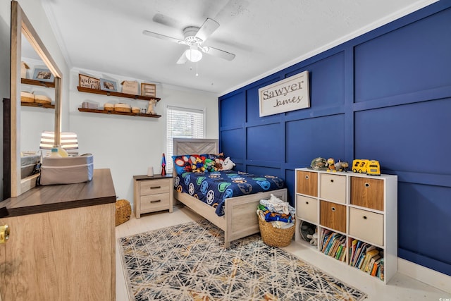 bedroom with ornamental molding, a ceiling fan, and a decorative wall