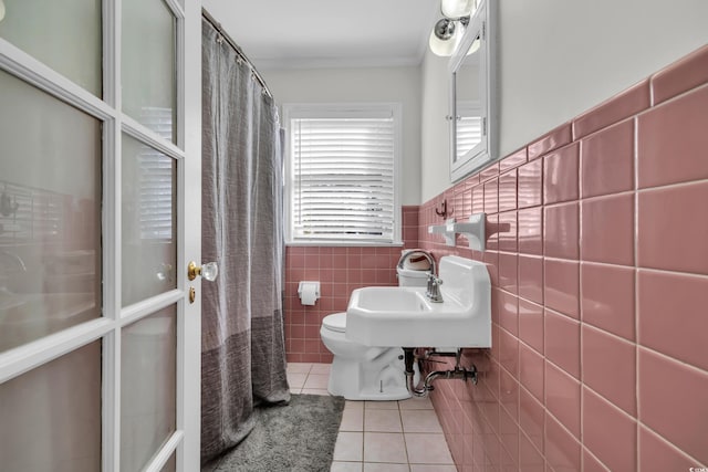 full bath with crown molding, tile walls, wainscoting, a sink, and tile patterned floors