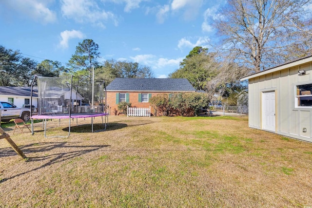 view of yard with a trampoline and fence