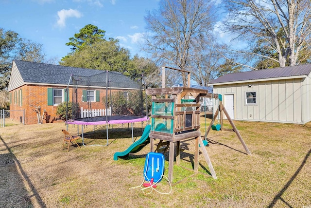 view of jungle gym featuring a yard, a trampoline, fence, and an outdoor structure