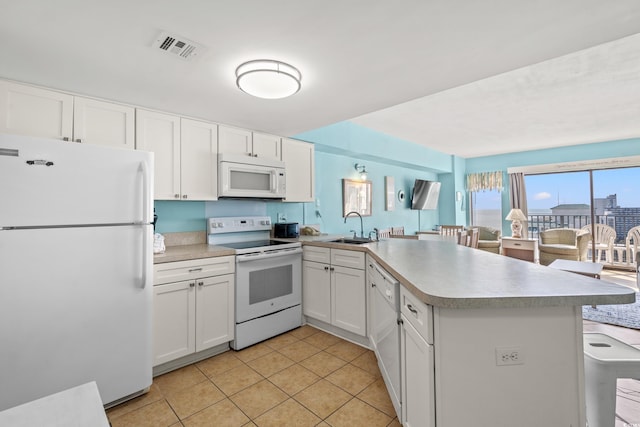 kitchen with sink, light tile patterned floors, kitchen peninsula, white appliances, and white cabinets