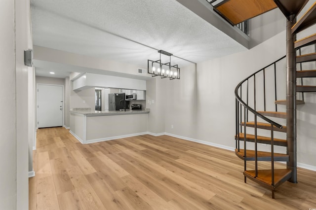 interior space with light hardwood / wood-style floors, a textured ceiling, and a chandelier