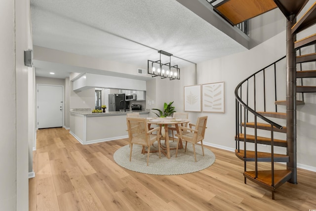 dining room featuring a textured ceiling, light hardwood / wood-style floors, and an inviting chandelier